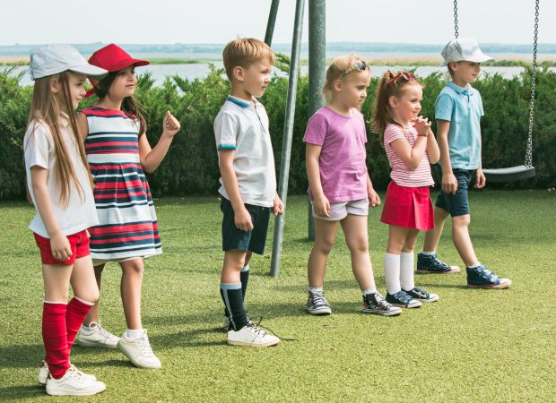 Funny starts. Kids fashion concept. The group of teen boys and girls standing at park. Children colorful clothes, lifestyle, trendy colors concepts.